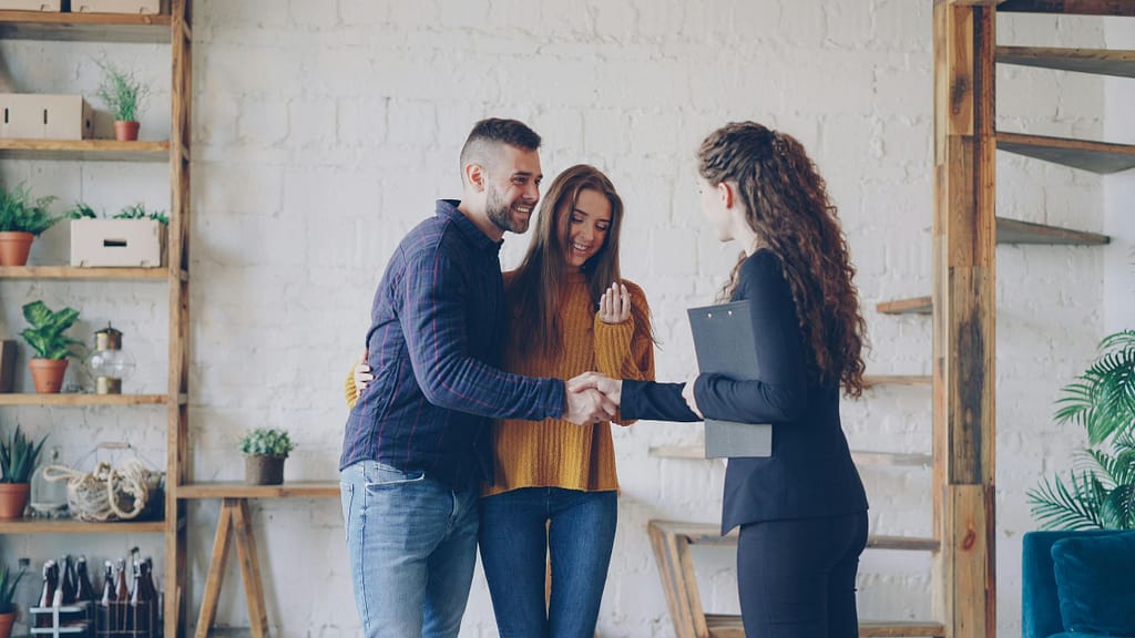 Happy couple shaking hands with listing agent after deciding not to sell house without agent
