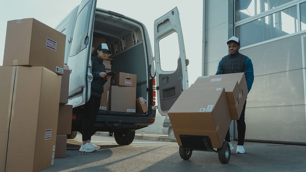 Two movers loading fragile-labeled boxes into a van, showing how to pack for a move safely