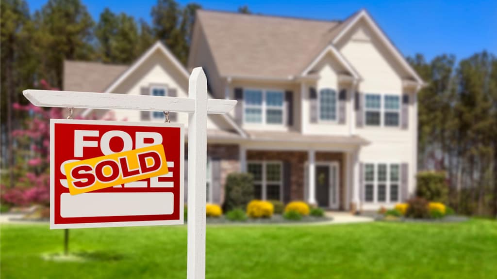 Steps to sell a home successfully shown by a sold sign in front of a house