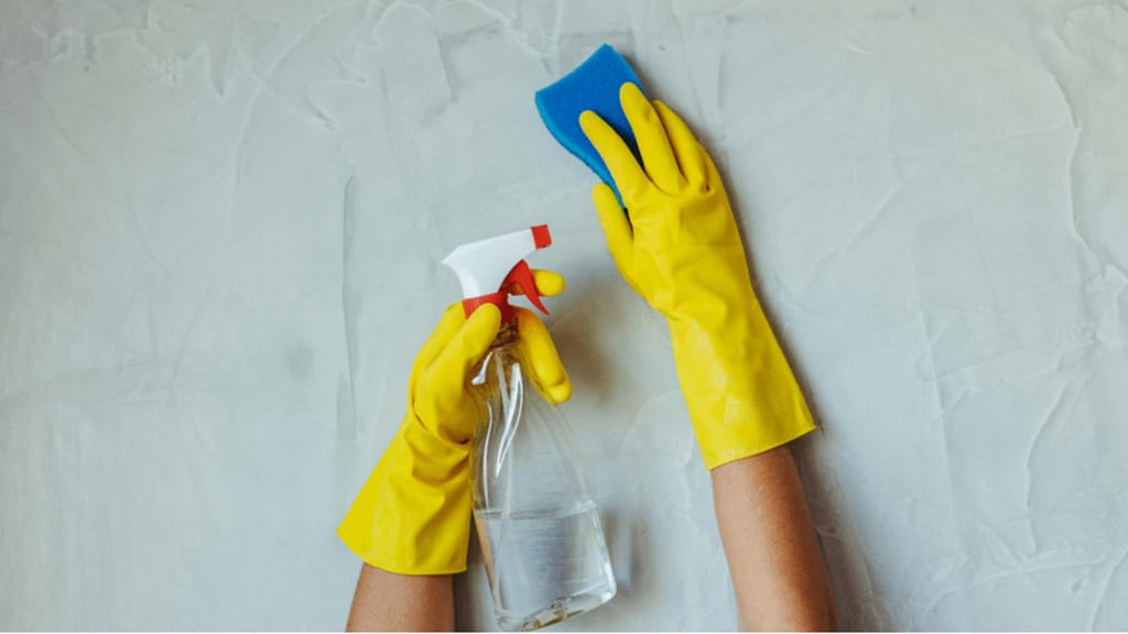 cleaning wall with sponge and spray during deep cleaning a house before selling