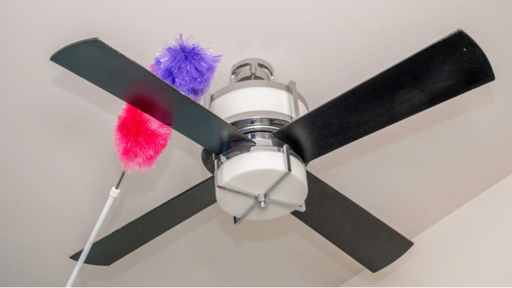 dusting ceiling fan during deep cleaning a house before selling