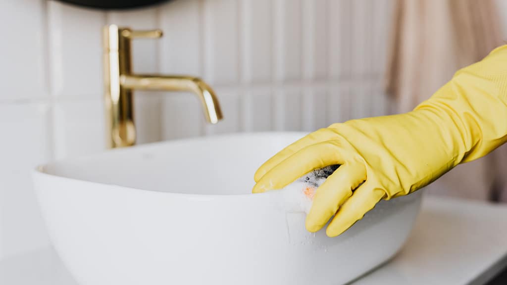 scrubbing bathroom sink during deep cleaning house