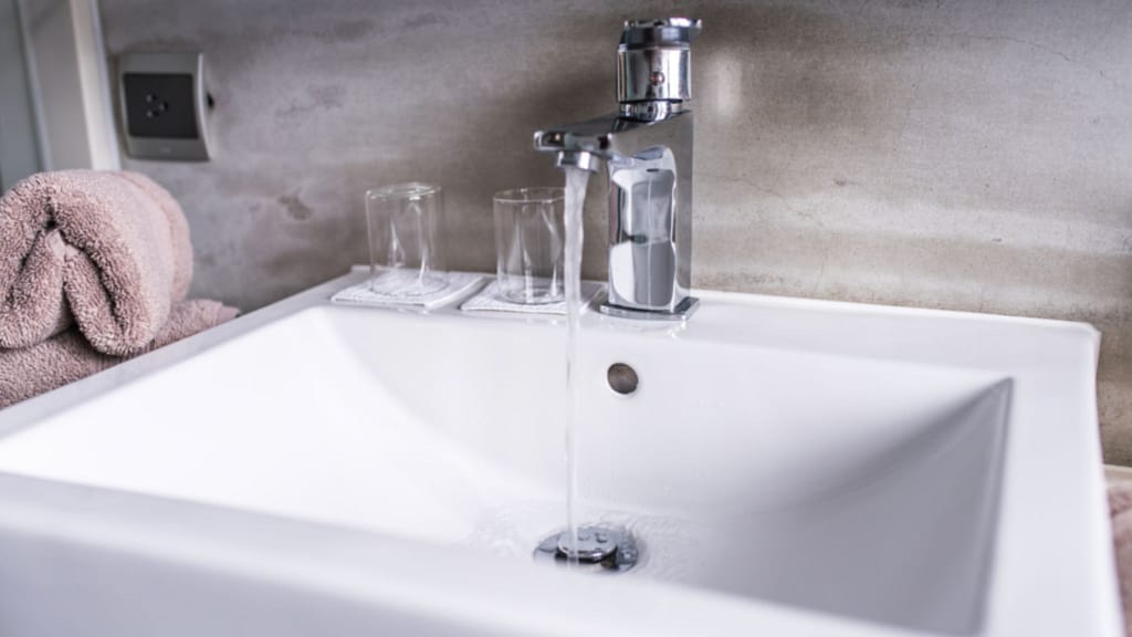 bathroom sink with water running showing sealed edges around basin
