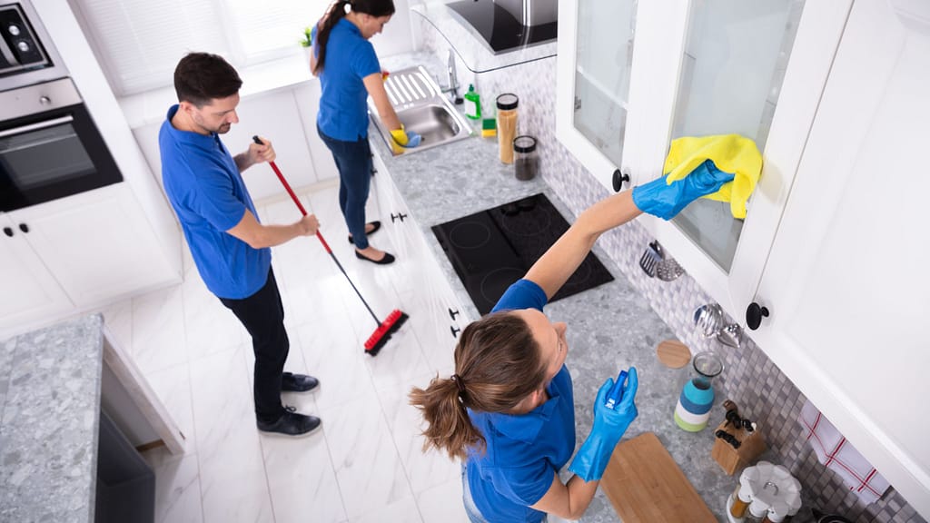 Professional cleaning team deep cleaning a new home kitchen before move-in