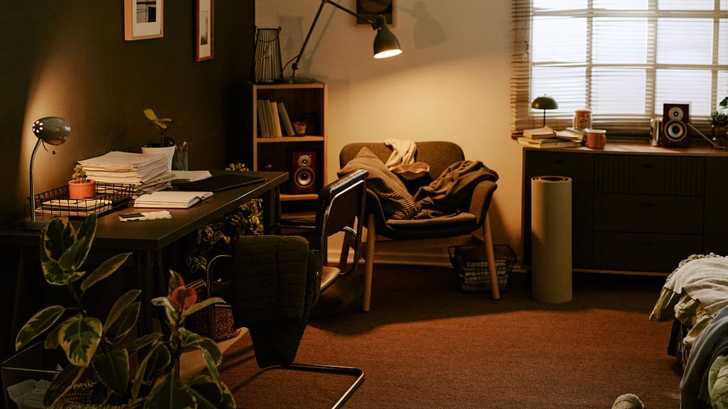 Cluttered room with overflowing desk, scattered items, and crowded surfaces