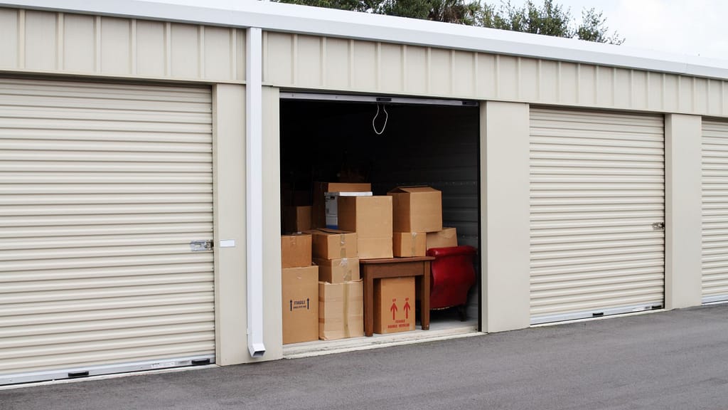 Open storage unit filled with labeled fragile boxes and a red leather chair, showing moving and packing tips for storage