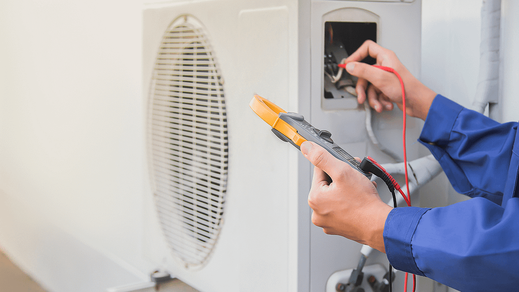 Technician testing an outdoor HVAC unit with a multimeter during a maintenance service call. How to reduce your energy bill