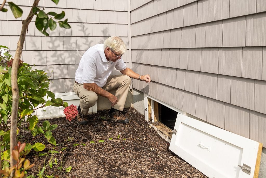 Homeowner checking a crawl space as part of a fall home maintenance checklist