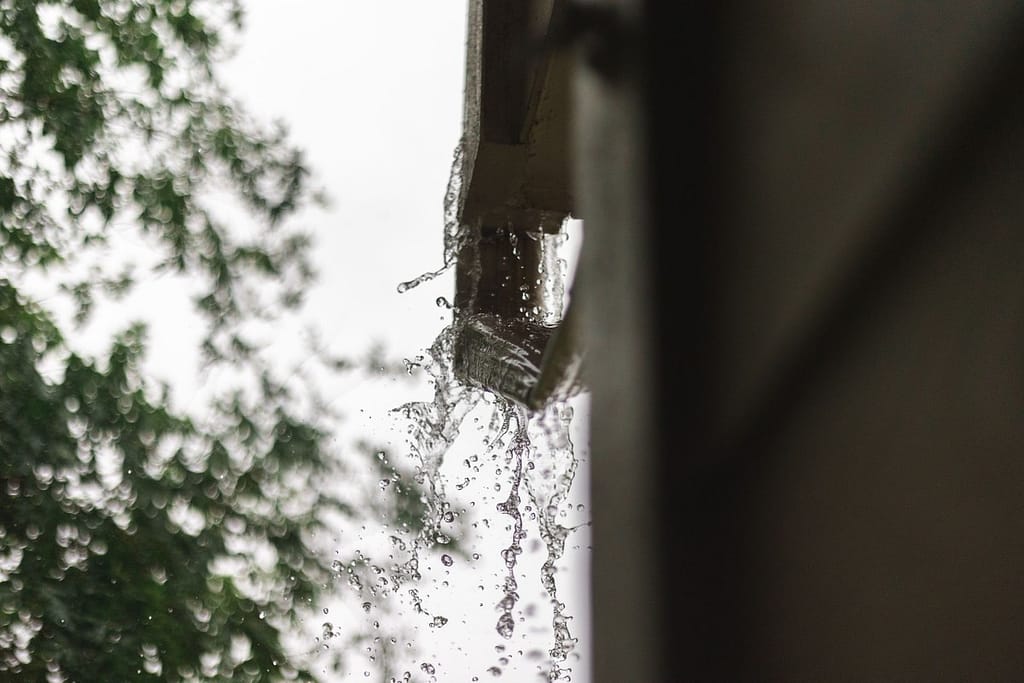 Rainwater overflowing from a roof gutter during heavy rain