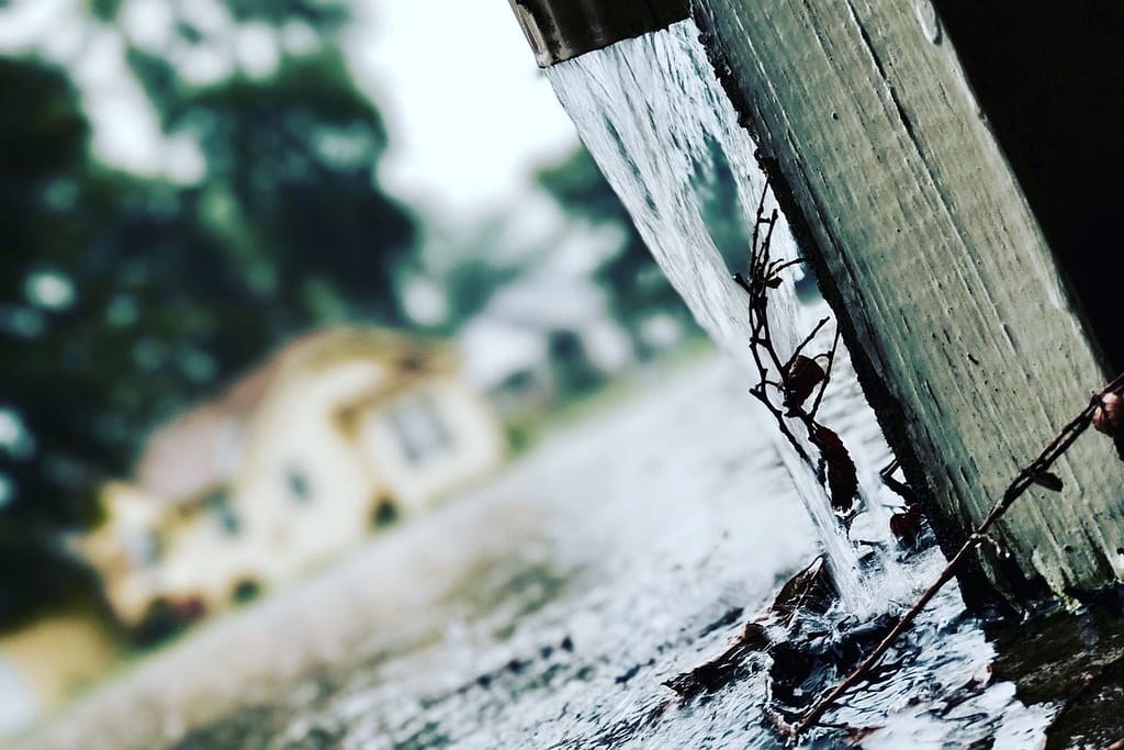 Rainwater draining beside a house without a downspout extension