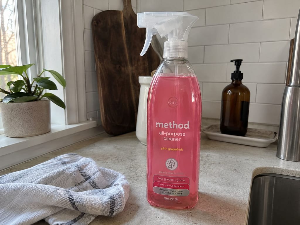 Method all-purpose cleaner pink grapefruit spray bottle on a kitchen counter near a sink and dish towel.