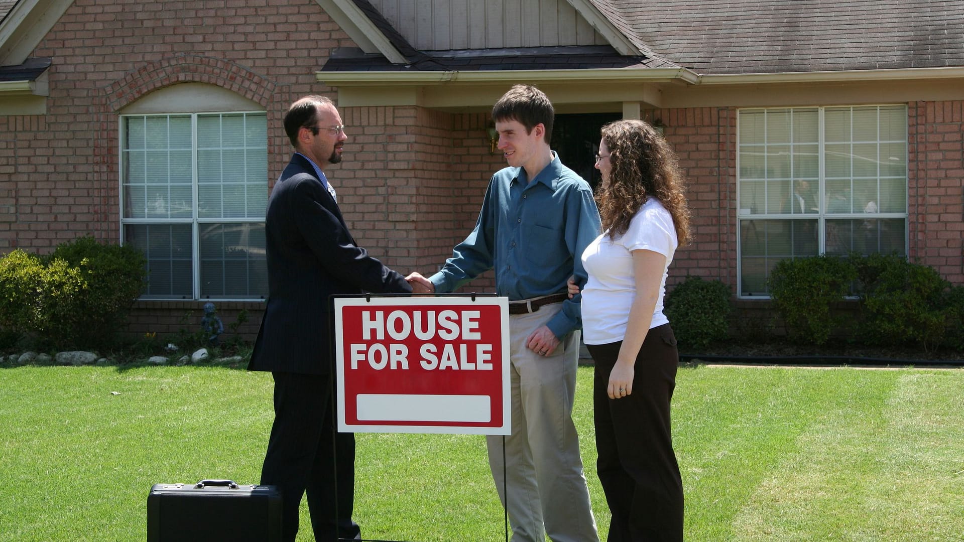 Happy couple shaking hands with listing agent after deciding not to sell house without agent