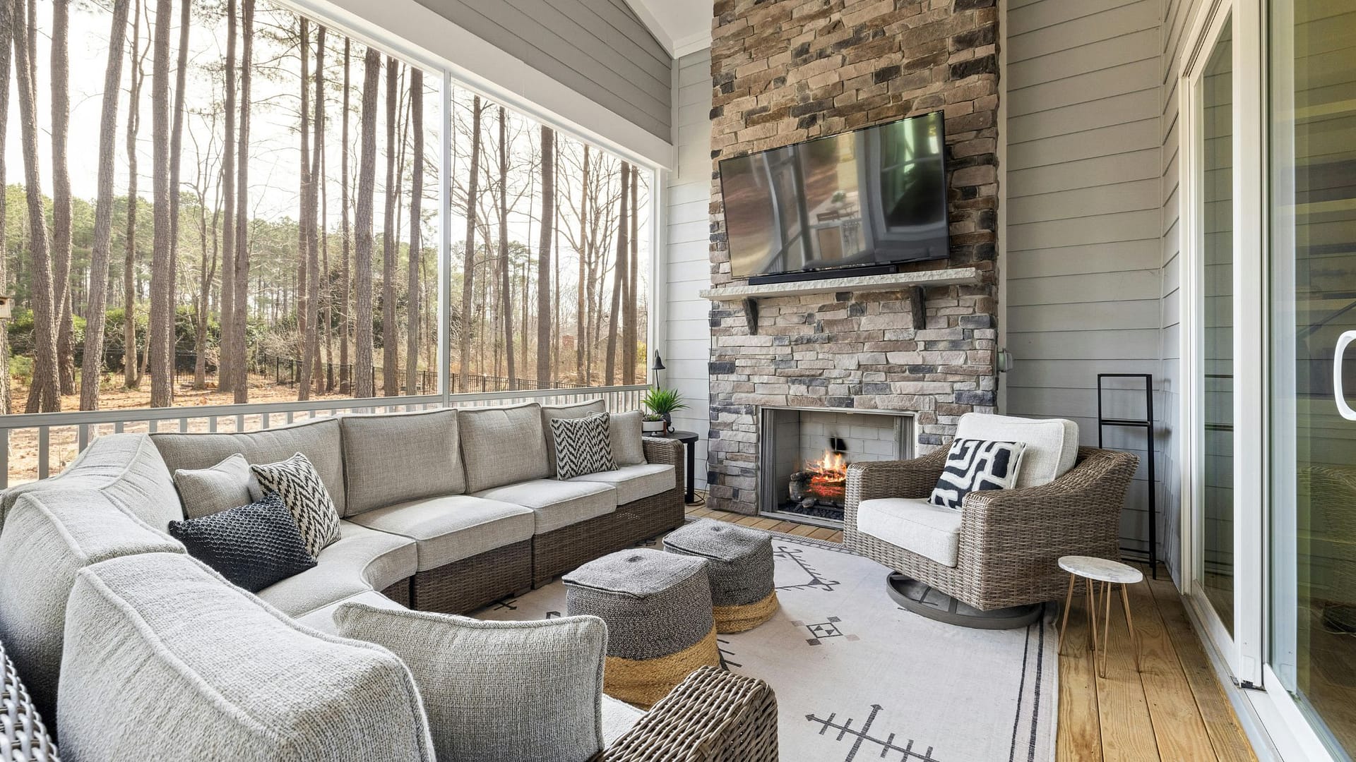 Large TV mounted high above stone fireplace on screened porch