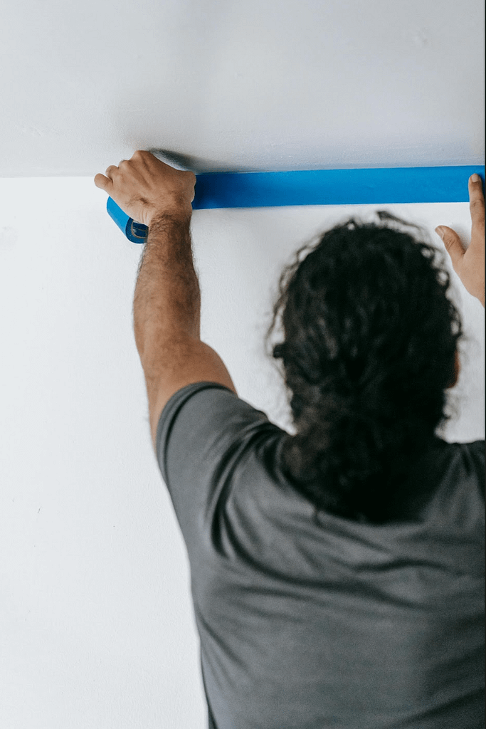 using masking tape to protect ceiling edge when preparing a room for painting (How to Use Painters Tape)