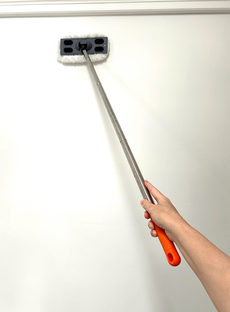 Cleaning walls before painting using a mop to remove dust and debris